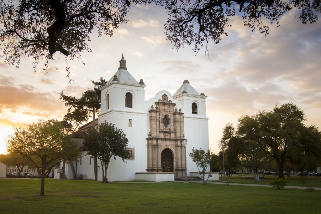 The Main Chapel at Joint Base San Antonio during sunrise - its two white cathedral towers accent its historic Mexican entryway